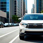 A young professional in appropriate attire, confidently standing next to their Toyota Highlander Hybrid in a bustling city street. Background features modern buildings and busy traffic. Safe for work, fully clothed, perfect anatomy, high quality.